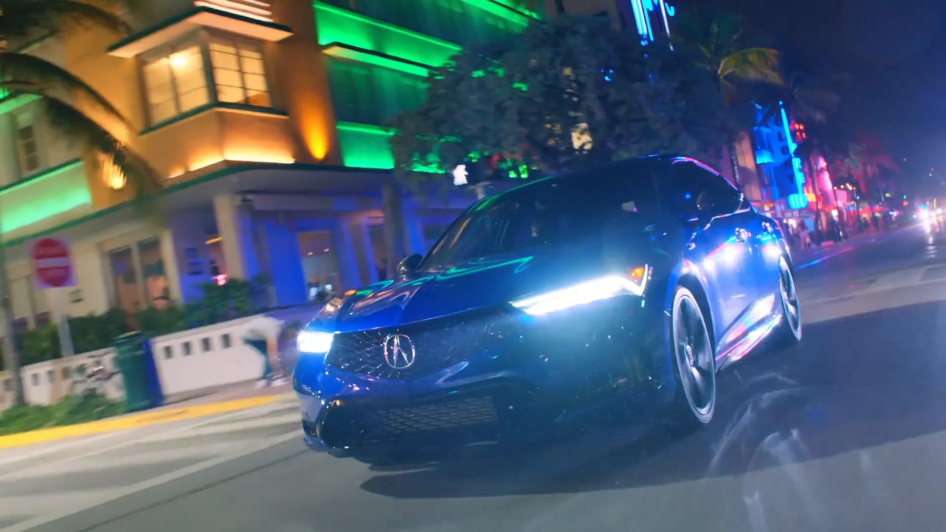 A red Integra under neon on a night street.