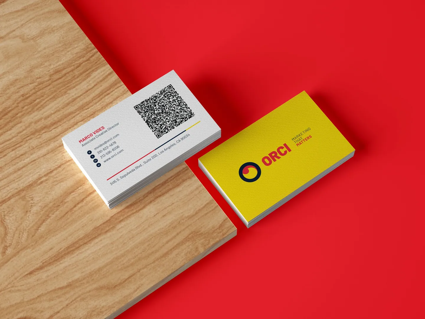 Orci business cards on wood against red.