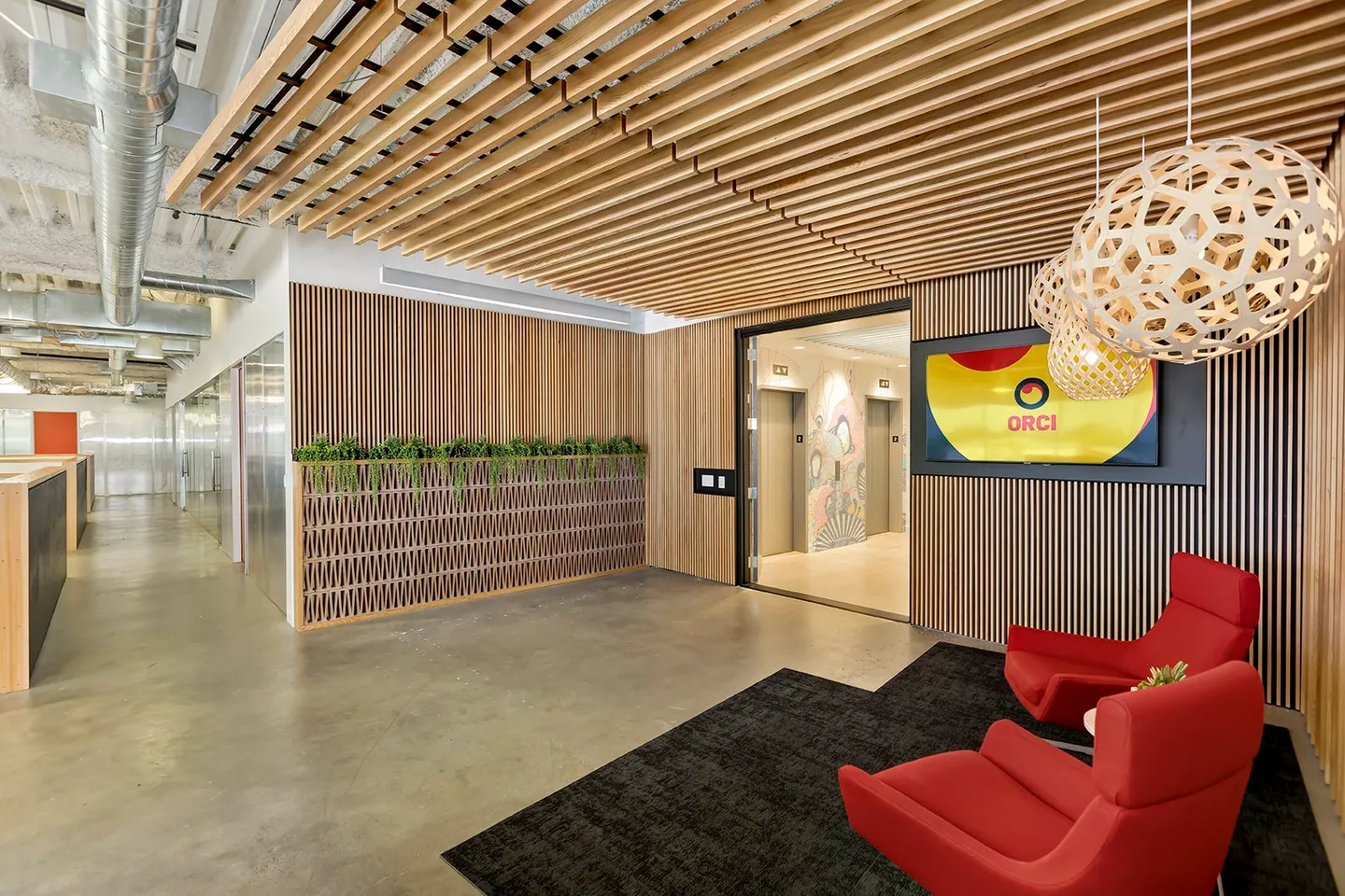 Orci lobby with red chairs and the new logo on a screen.