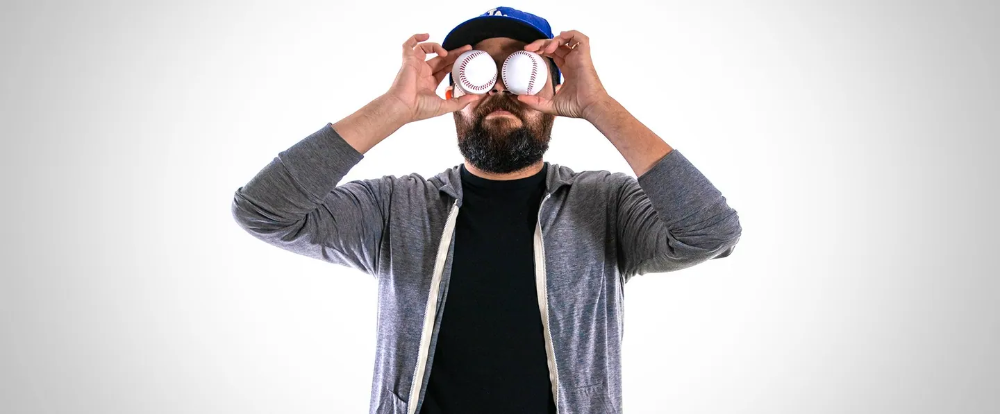 Team portrait: a man in a cap holding two donuts over his eyes.