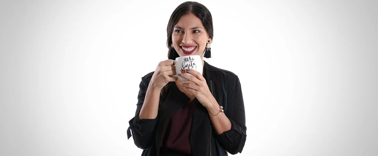 Team portrait: a woman smiling behind a coffee mug.
