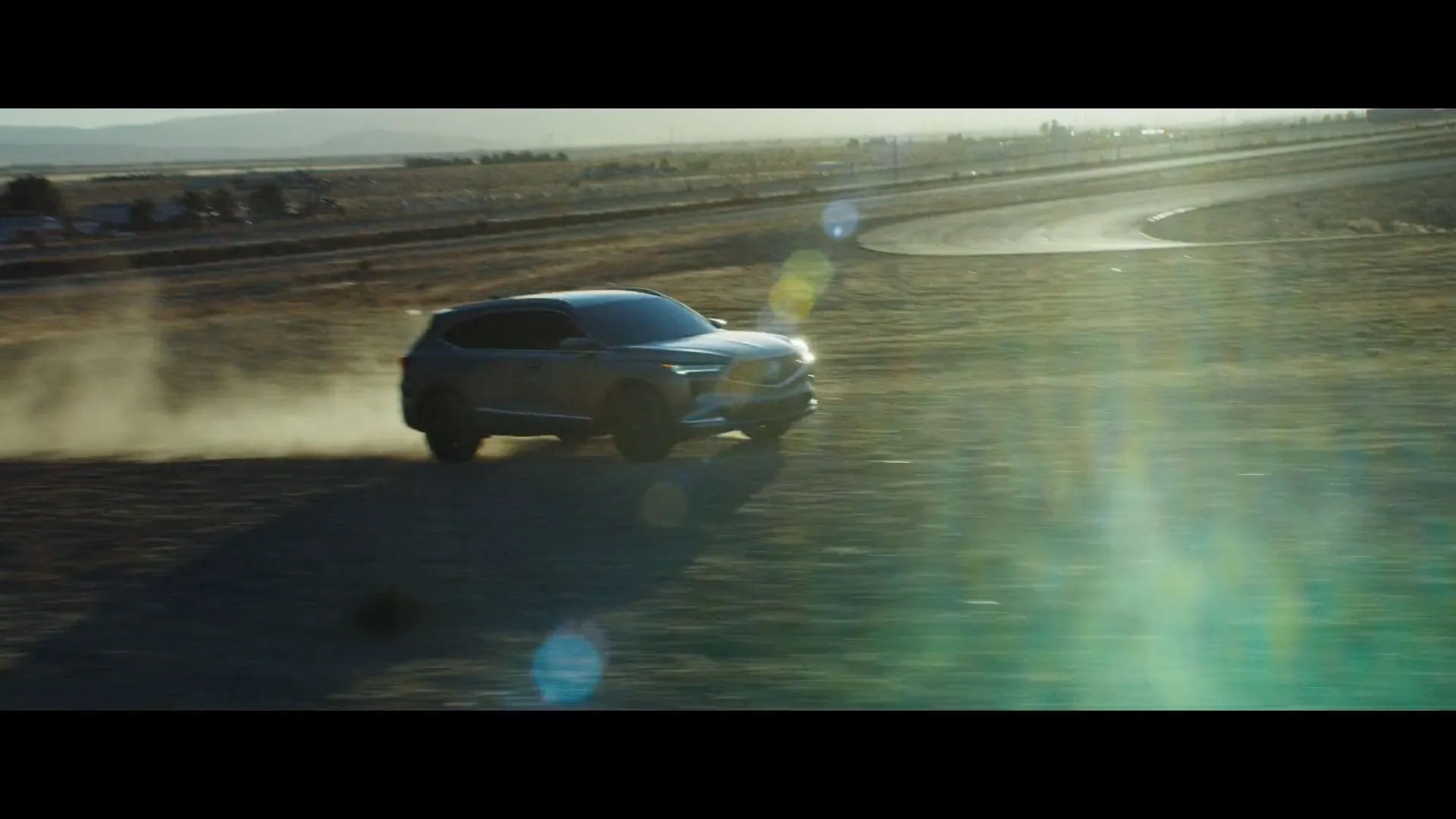 An Acura MDX drifts through desert dust on a closed course.
